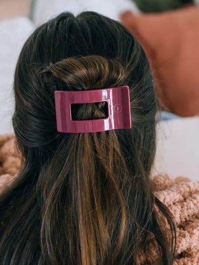 Maroon rectangle hair clip in woman's hair.