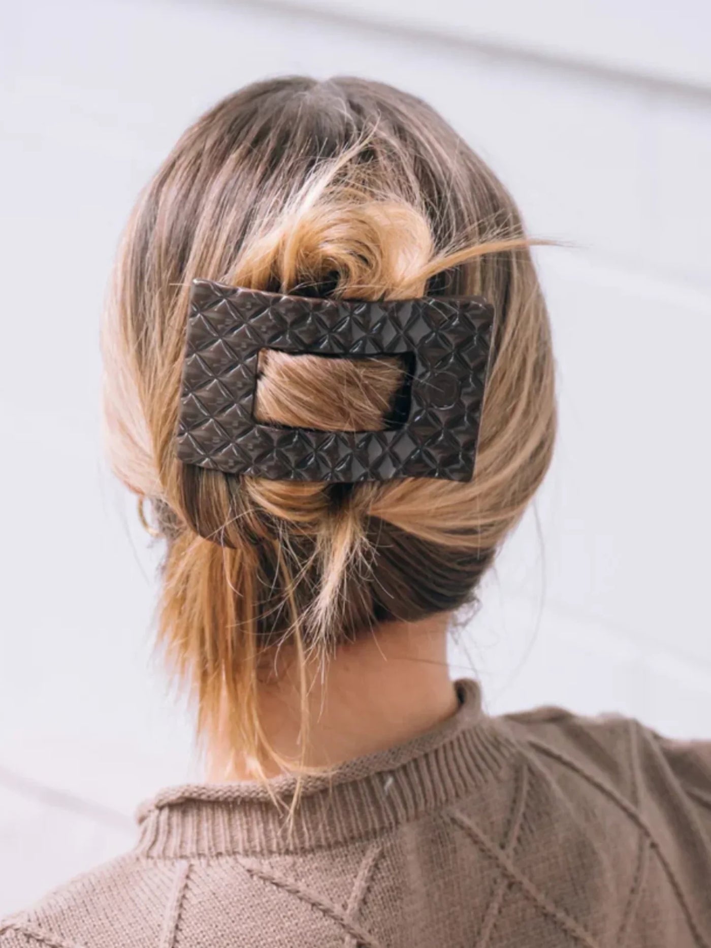 Woman with updo featuring dark brown large rectangle hair clip on white background.