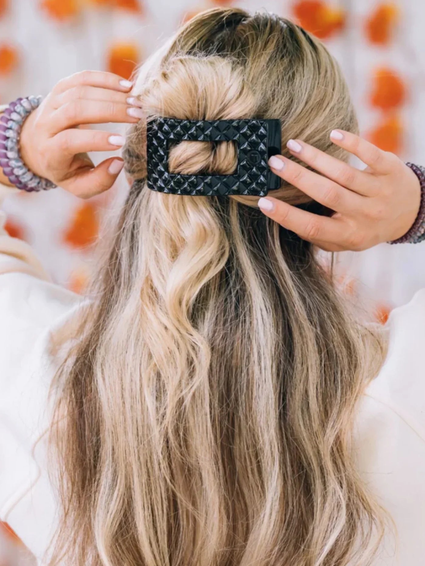 Black quilted rectangle hair clip in woman's hair.