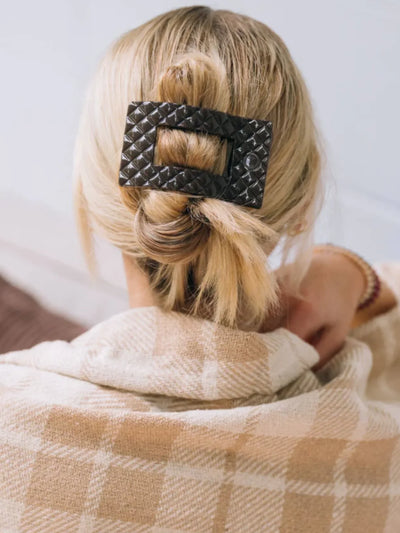 Brown quilted rectangle hair clip in woman's hair.