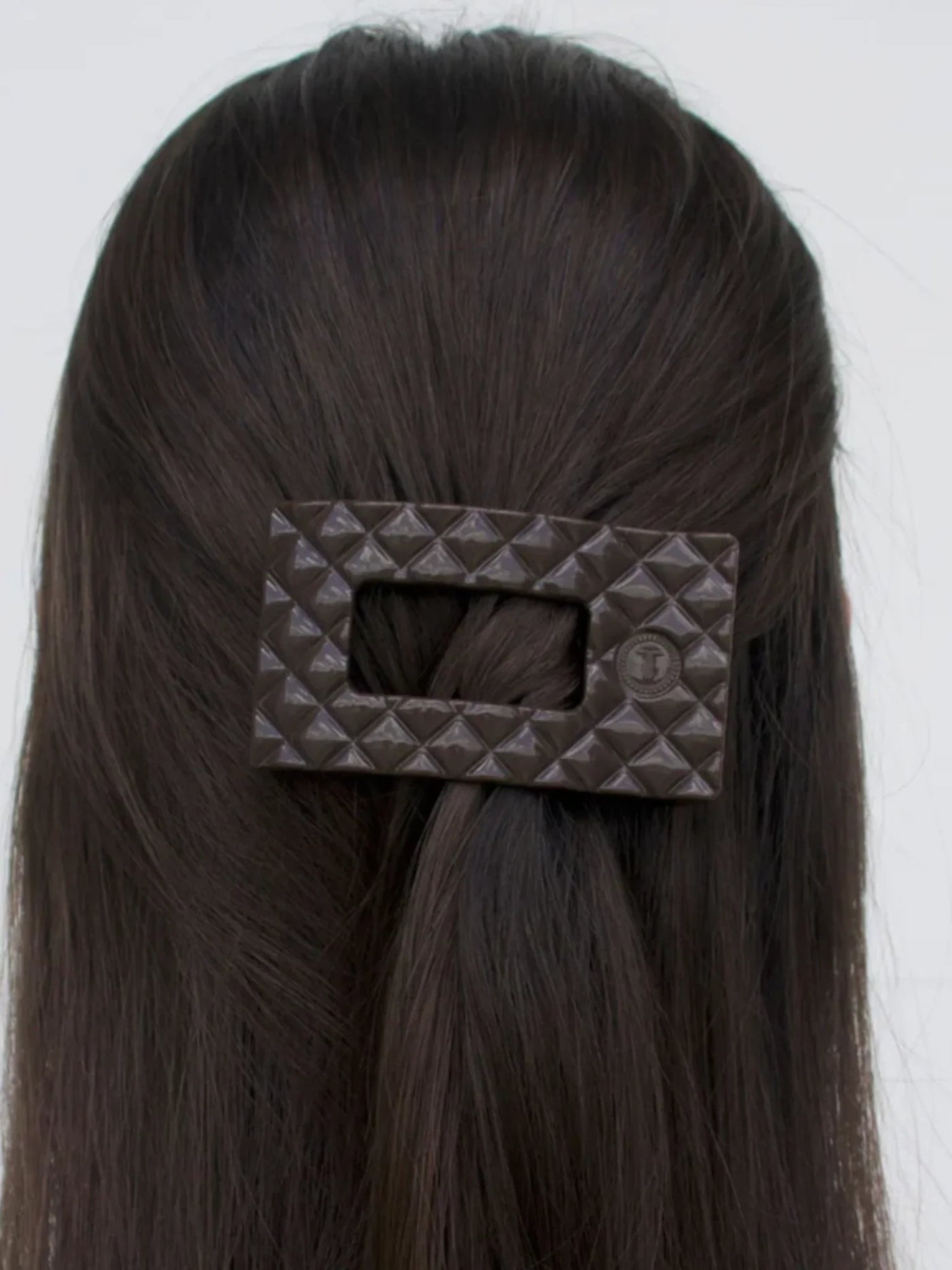 Dark brown quilted small rectangle hair clip in model's half-up hairstyle.