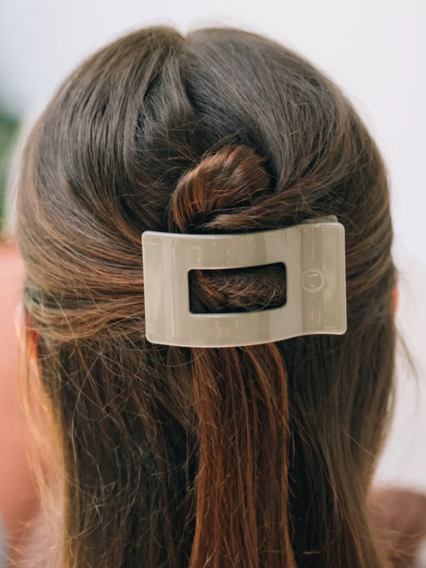Sage green small rectangle hair clip in woman's half-up hairdtyle.