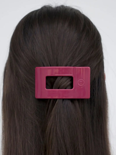 Maroon small rectangle hair clip in woman's half-up hairstyle.