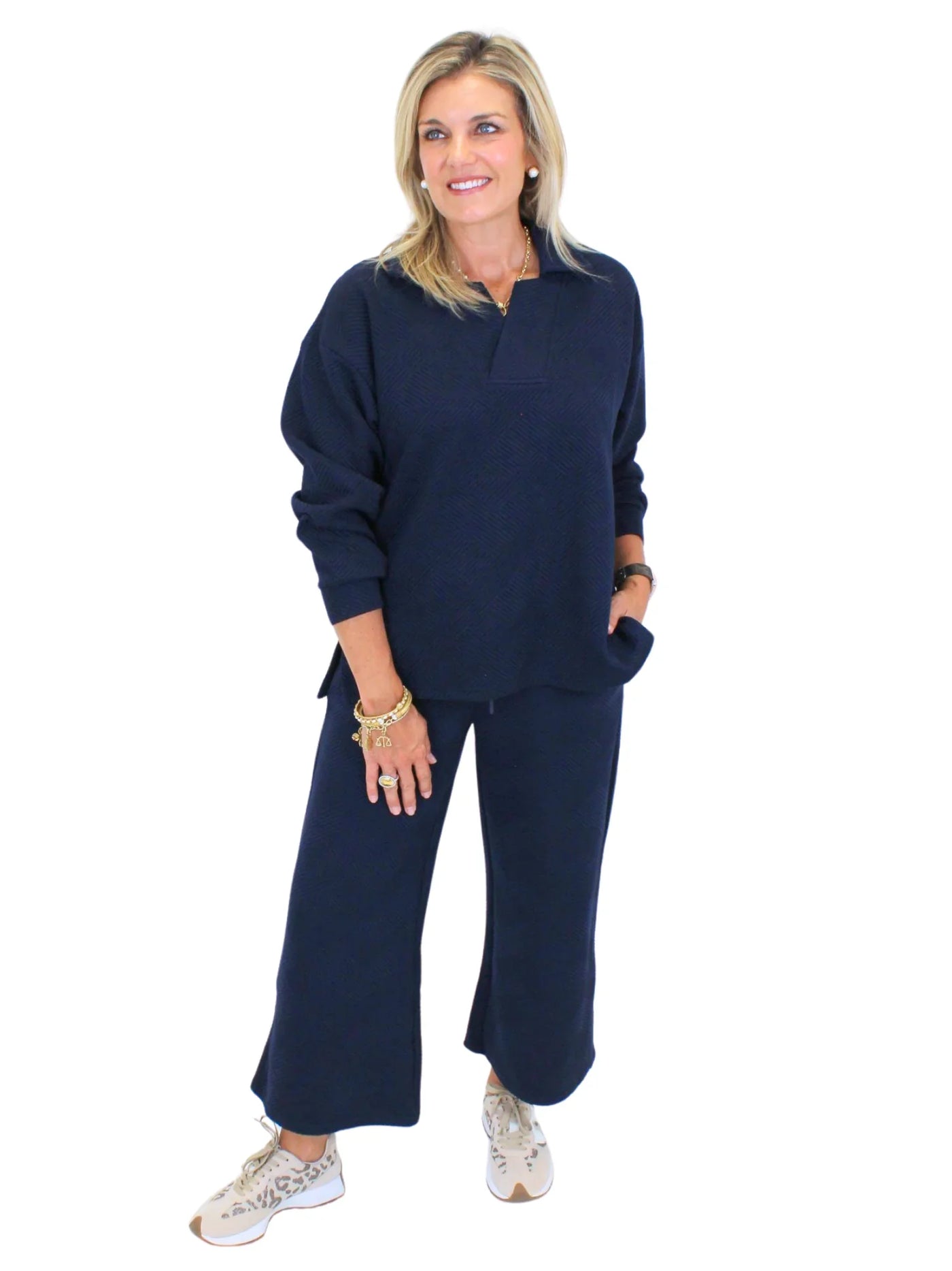 Model wearing textured navy sweatshirt and textured navy pants on white background, angled front.