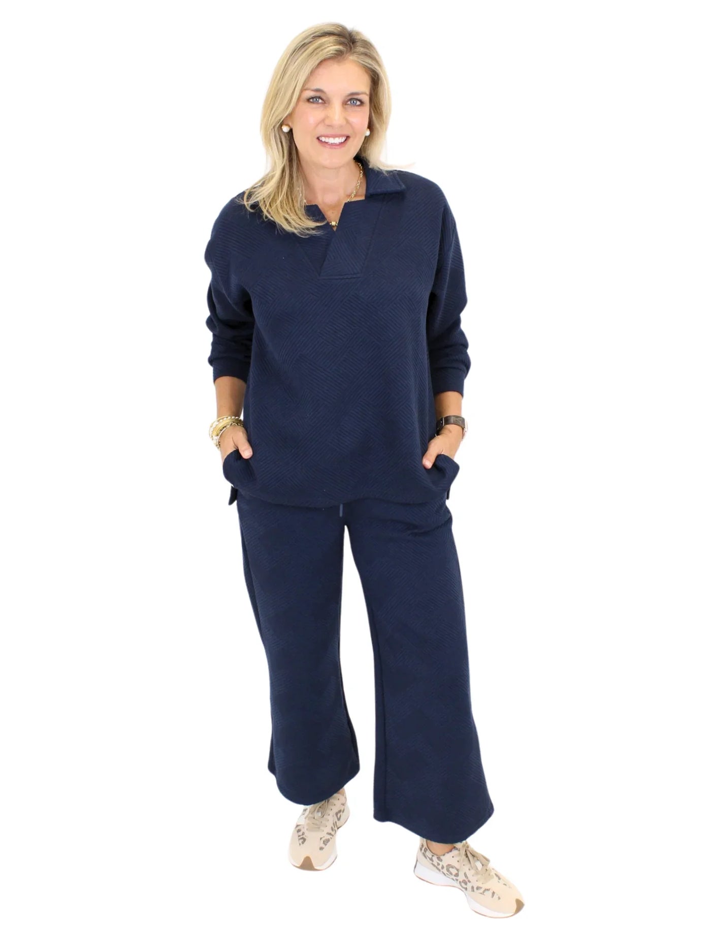 Model wearing textured navy sweatshirt and textured navy pants on white background, front.