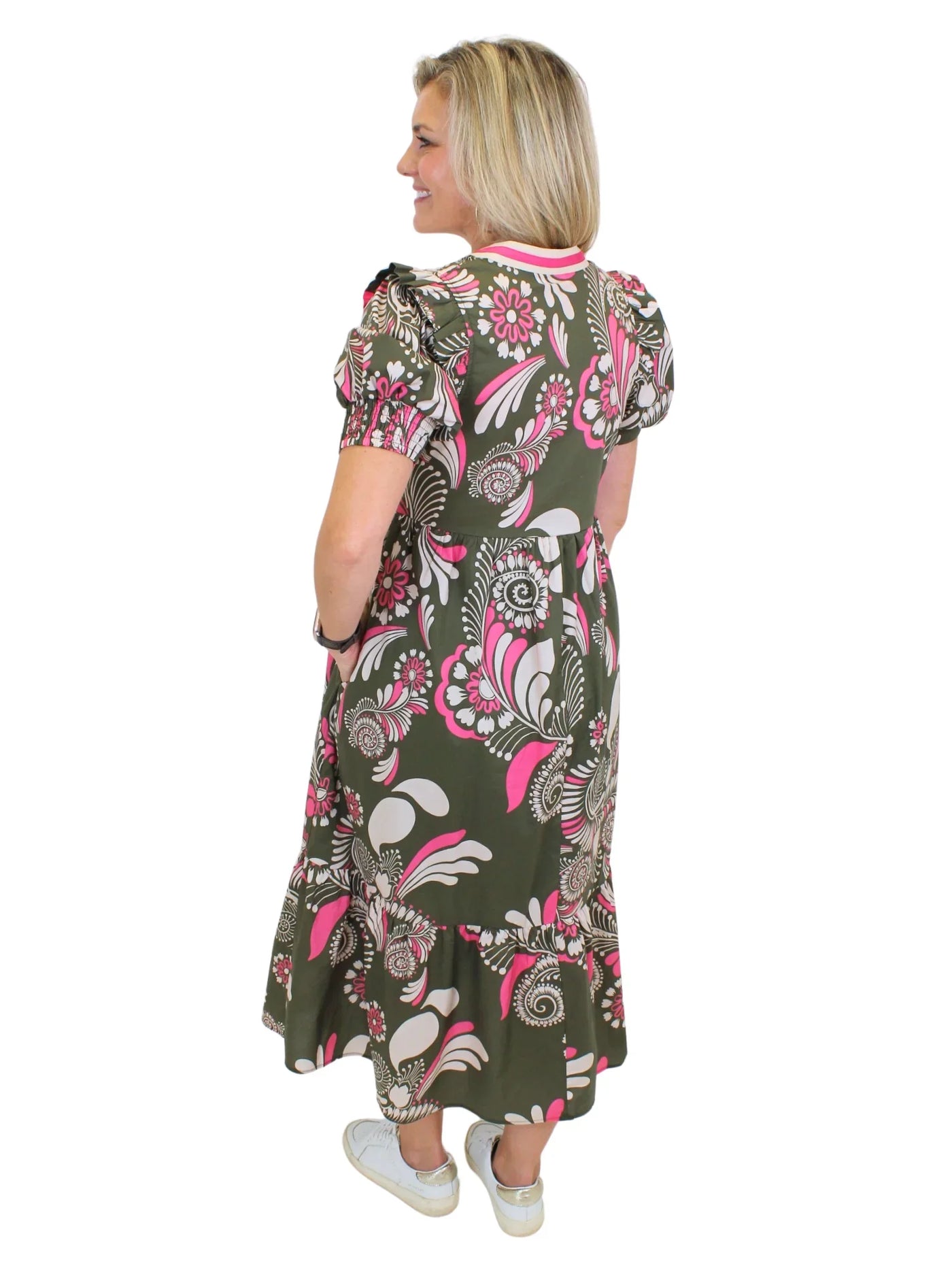 Model wearing green and pink floral midi dress with hand in pocket on white background, back.