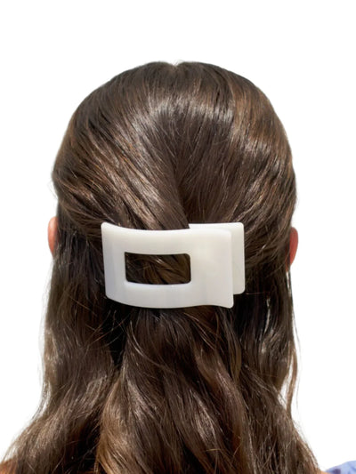 White small rectangular hair clip in model's hair.