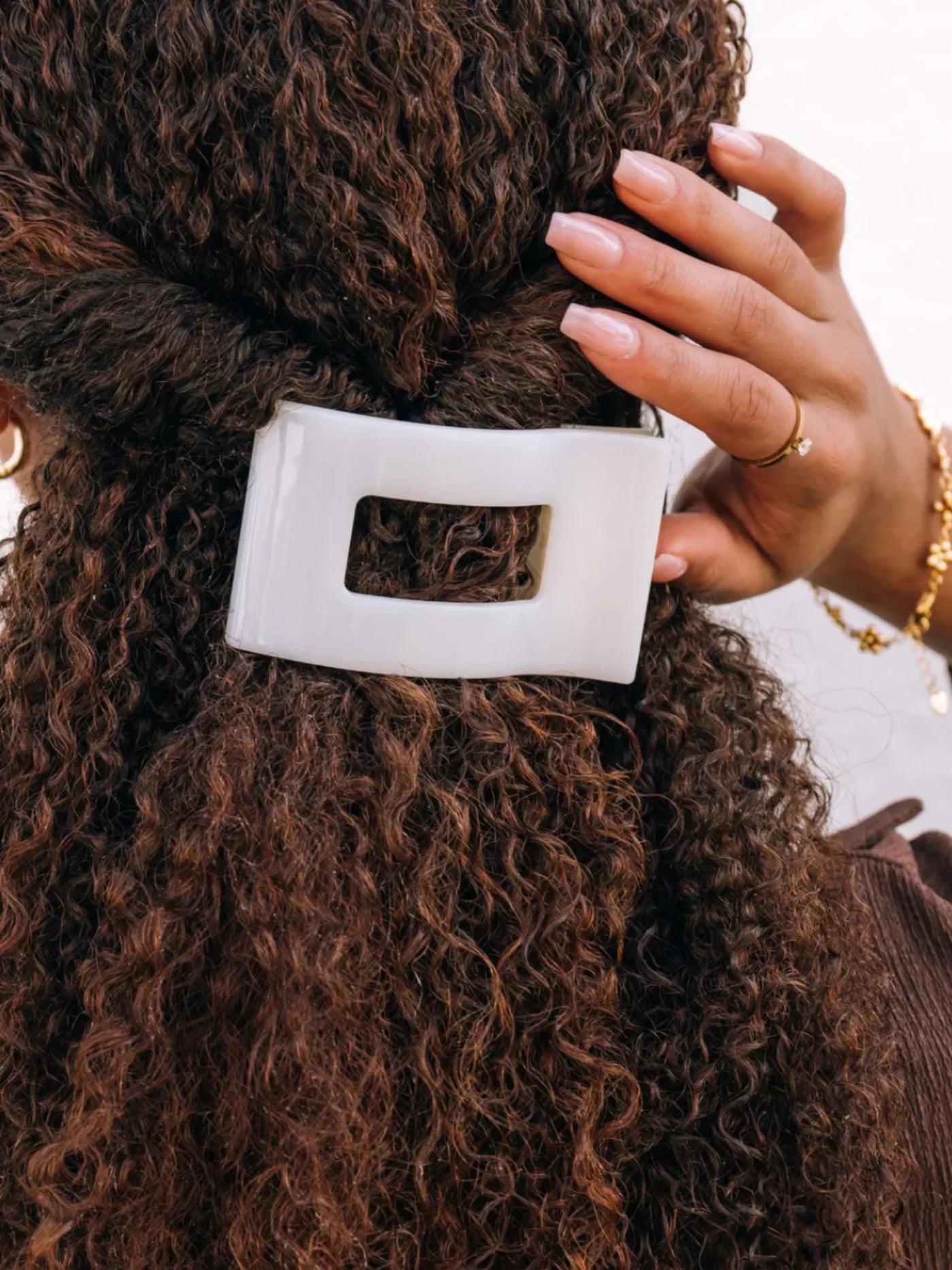 Close-up of a person with curly hair wearing a white medium rectangle hair clip.