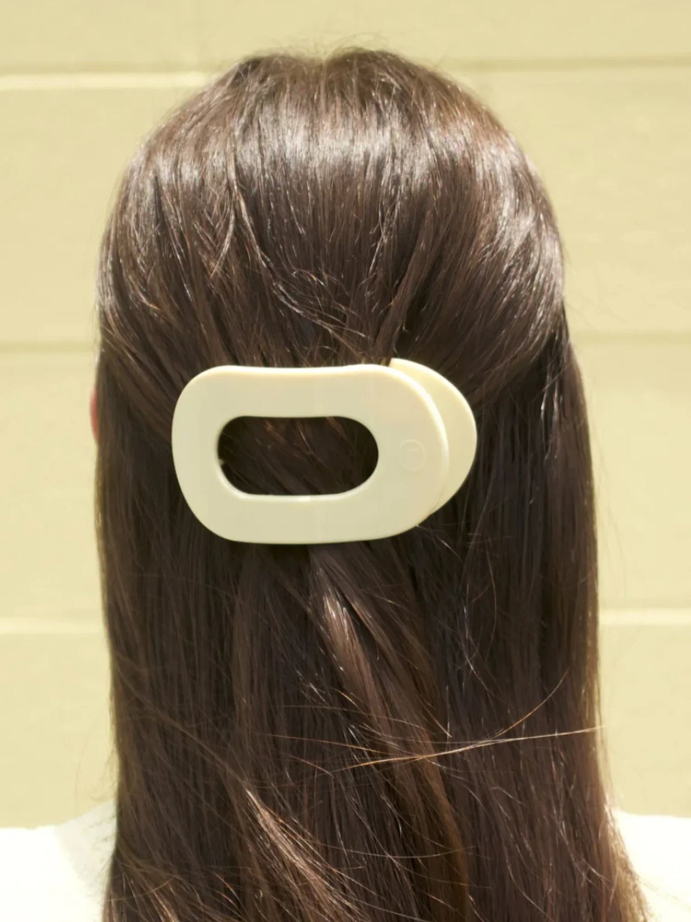 Small yellow round hair clip in model's hair.