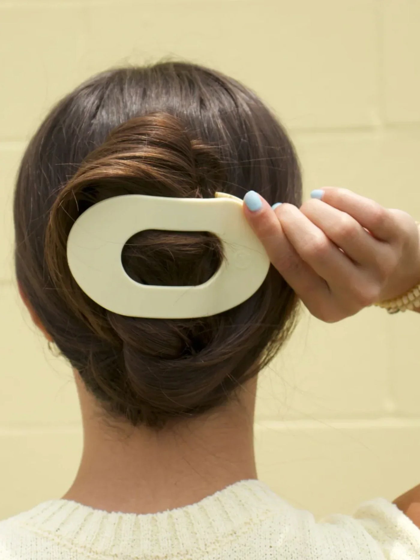 Yellow large round hair clip in model's hair.