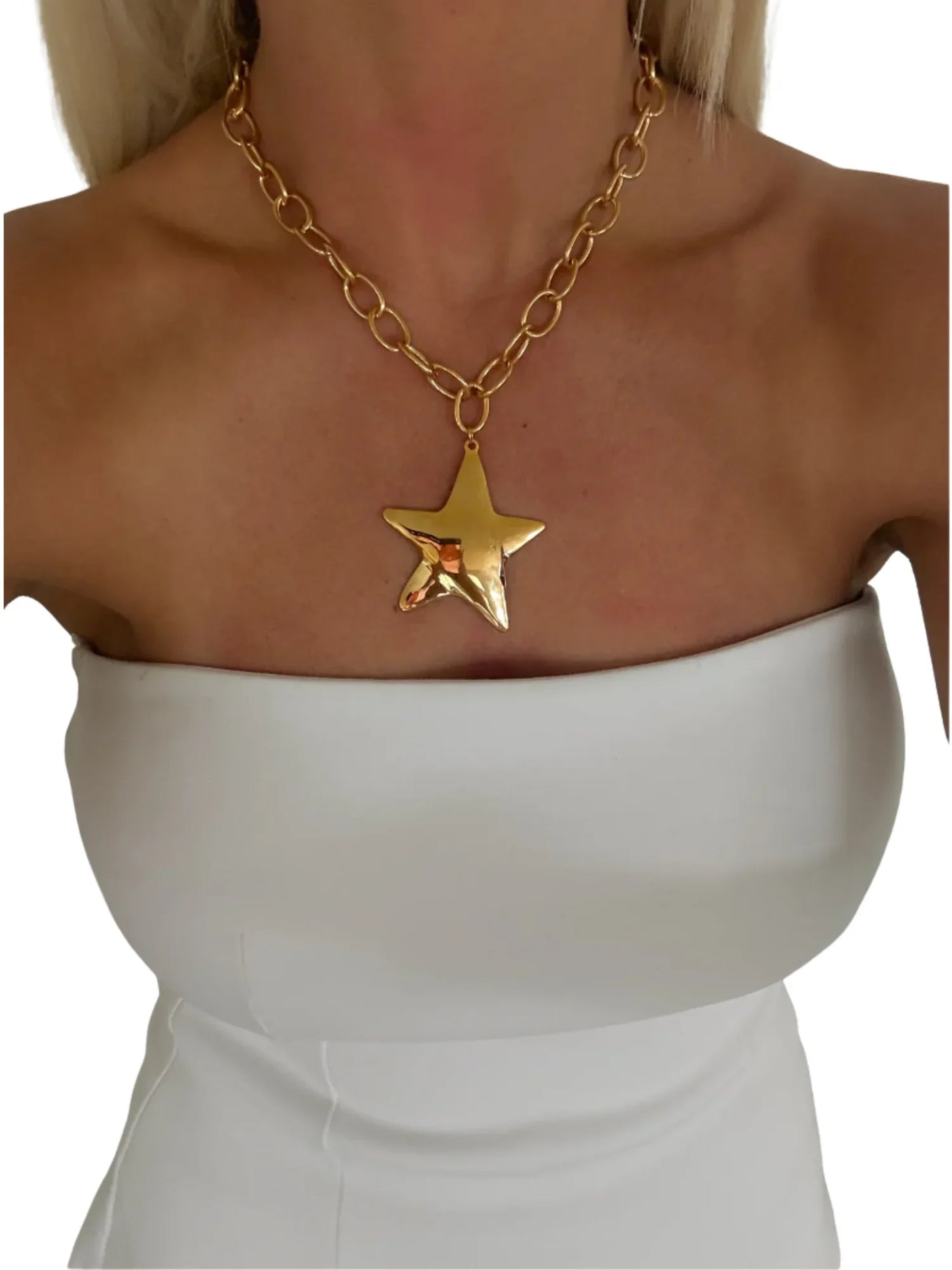 Chunky gold star necklace on model wearing a white top on white background.