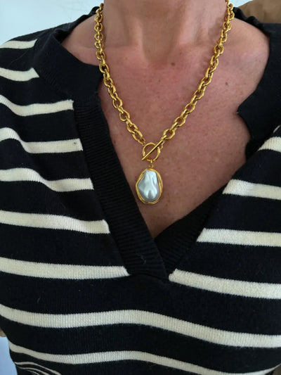 Model wearing old chunky chain toggle necklace with nugget pearl pendant.