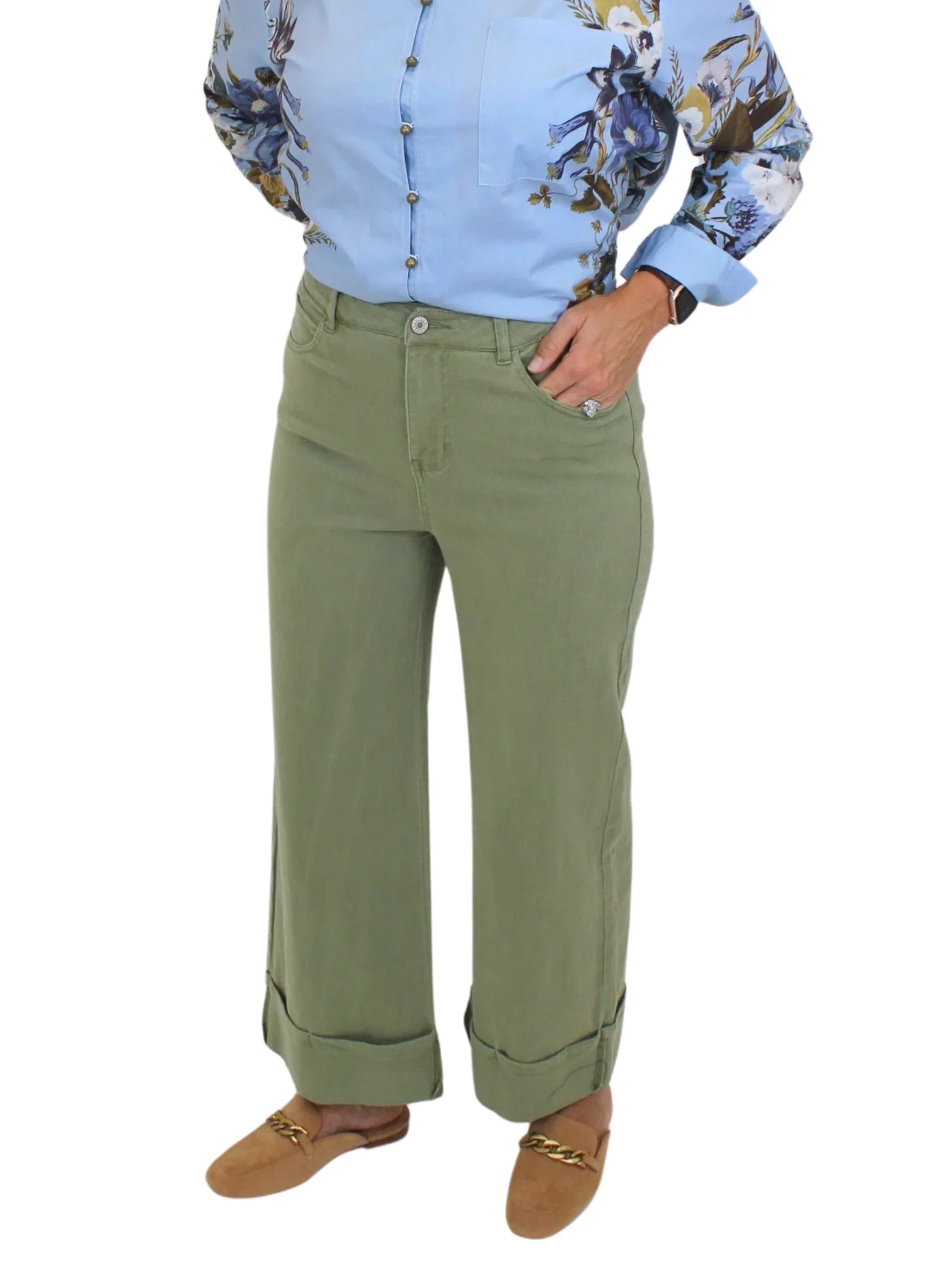 Model wearing blue blouse tucked into green wide leg cuffed jeans on white background, closeup front.