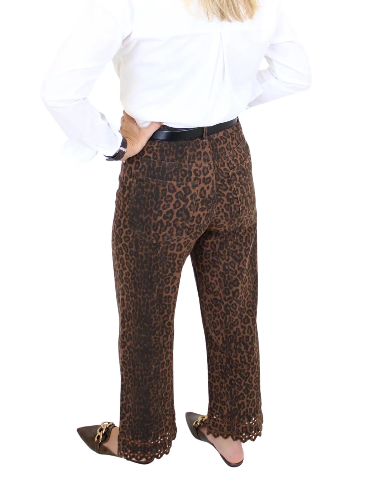 Woman wearing leopard print pants and white blouse on a white background, closeup back.