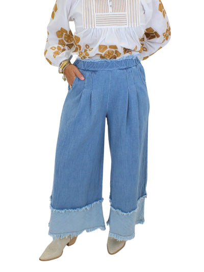 Model wearing pull-on wide leg raw hem jeans on white background, closeup front.