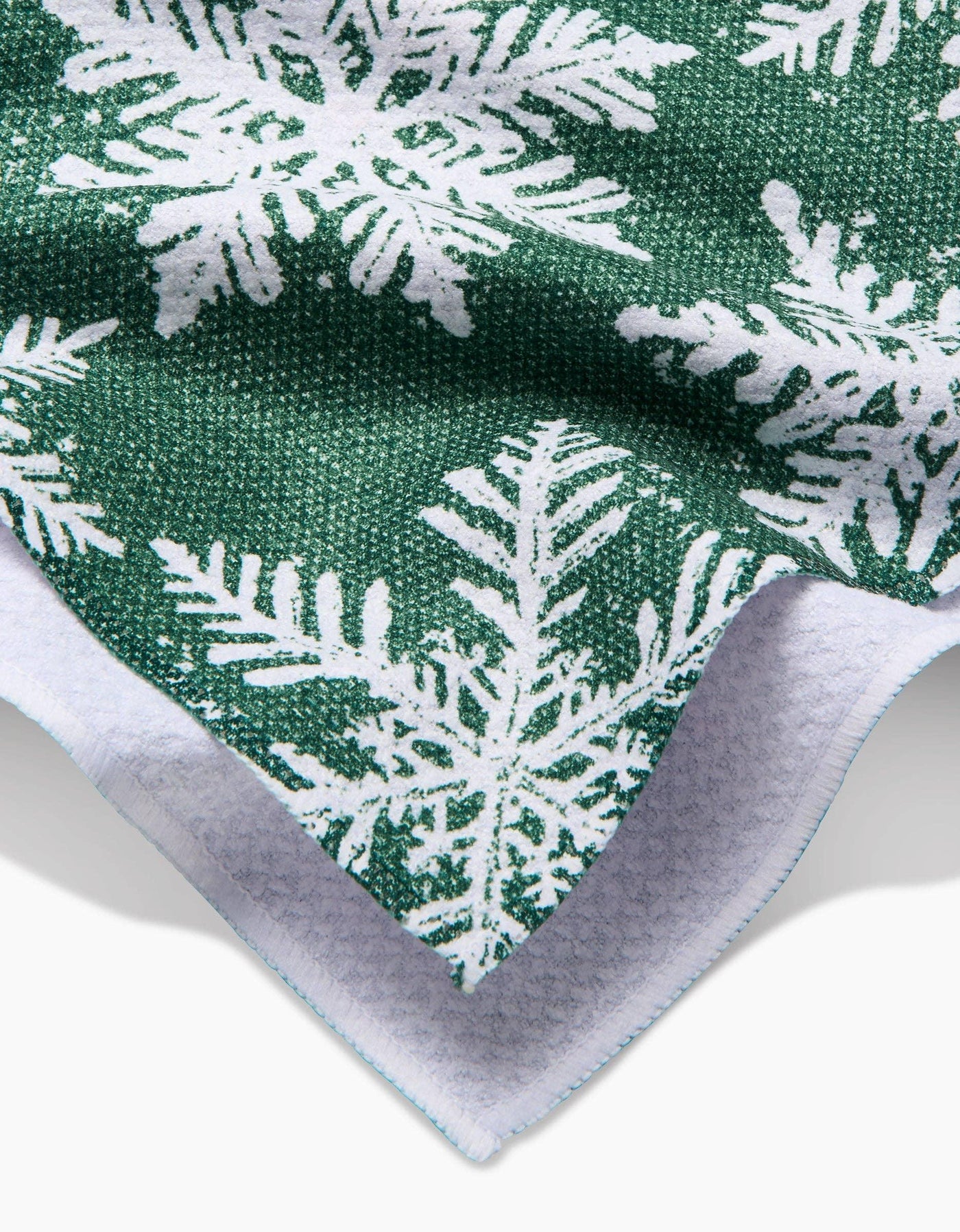 Closeup green tea towel with white snowflake pattern on a white background