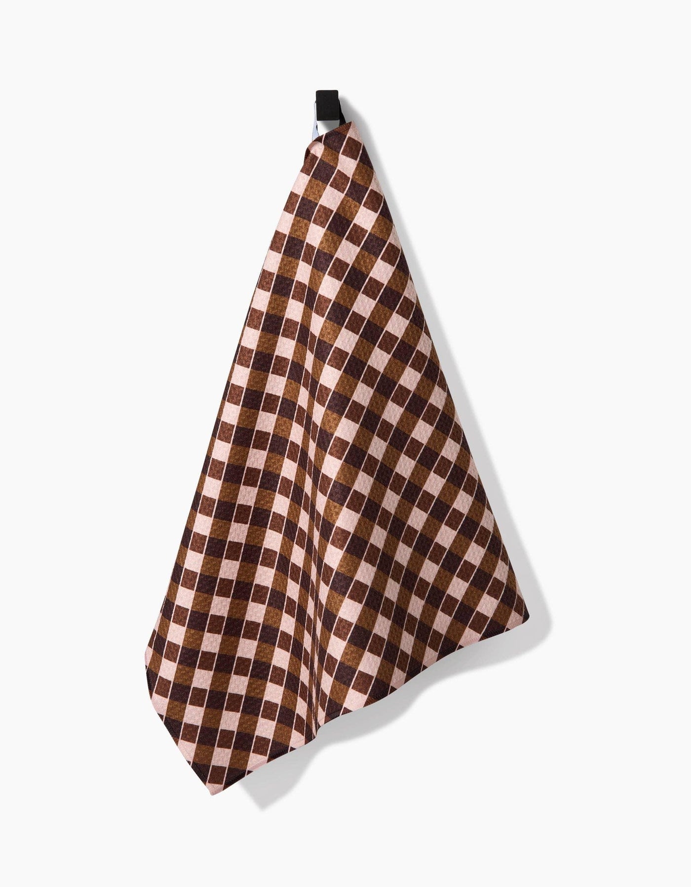 Checkered patterned tea towel with brown and beige colors hanging on a white background