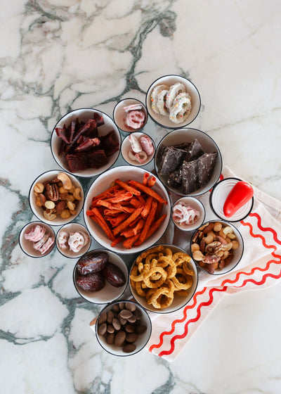 Assorted snacks in small bowls on a marble surface