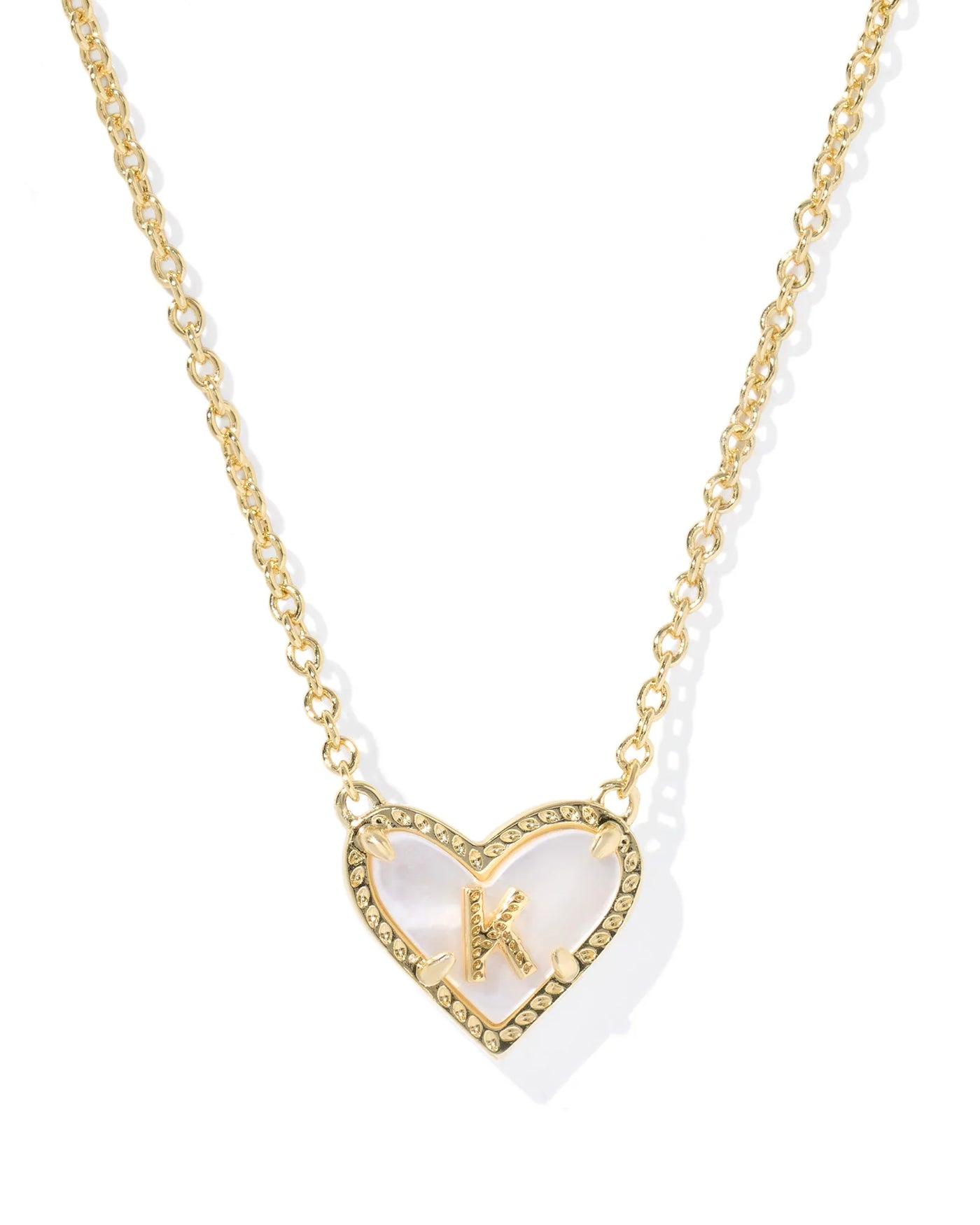 Gold necklace with a heart-shaped pendant and letter "K"on a white background.