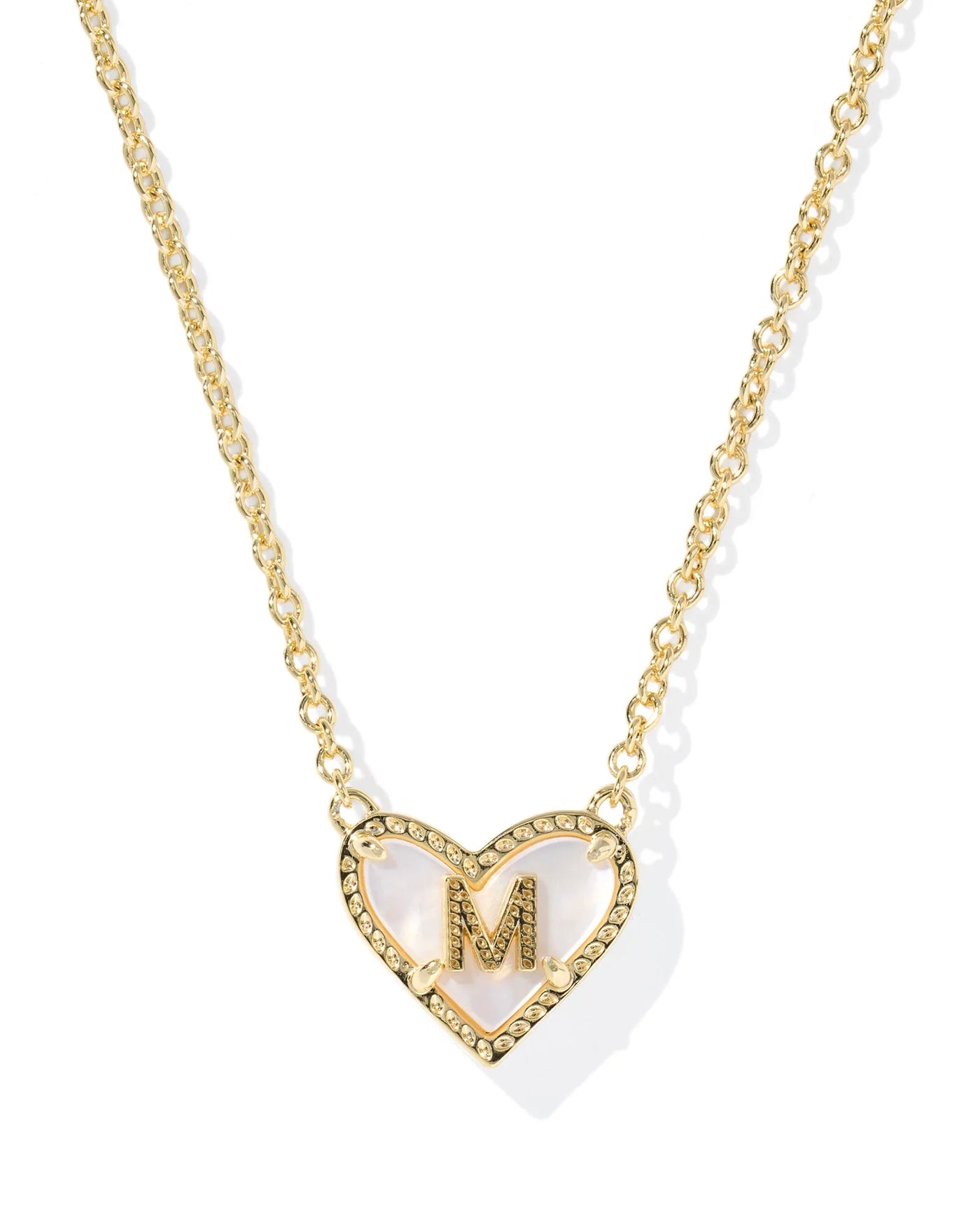 Gold necklace with a heart-shaped pendant featuring the letter 'M' on a white background.