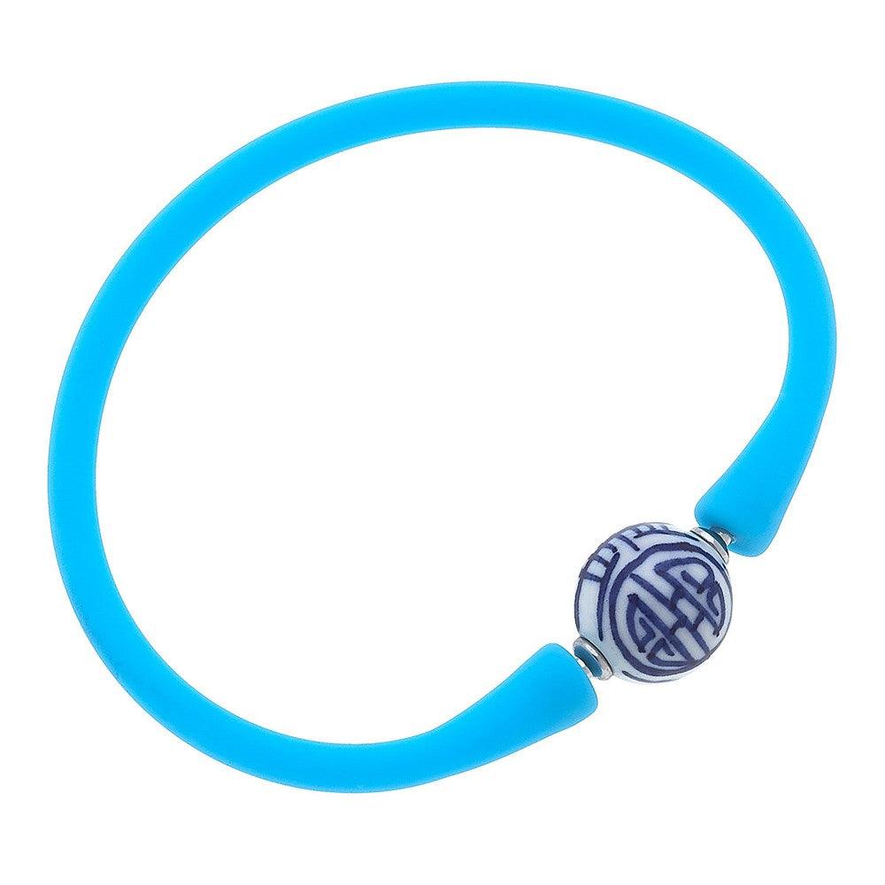 Bright blue silicone bracelet with a small chinoiserie bead]