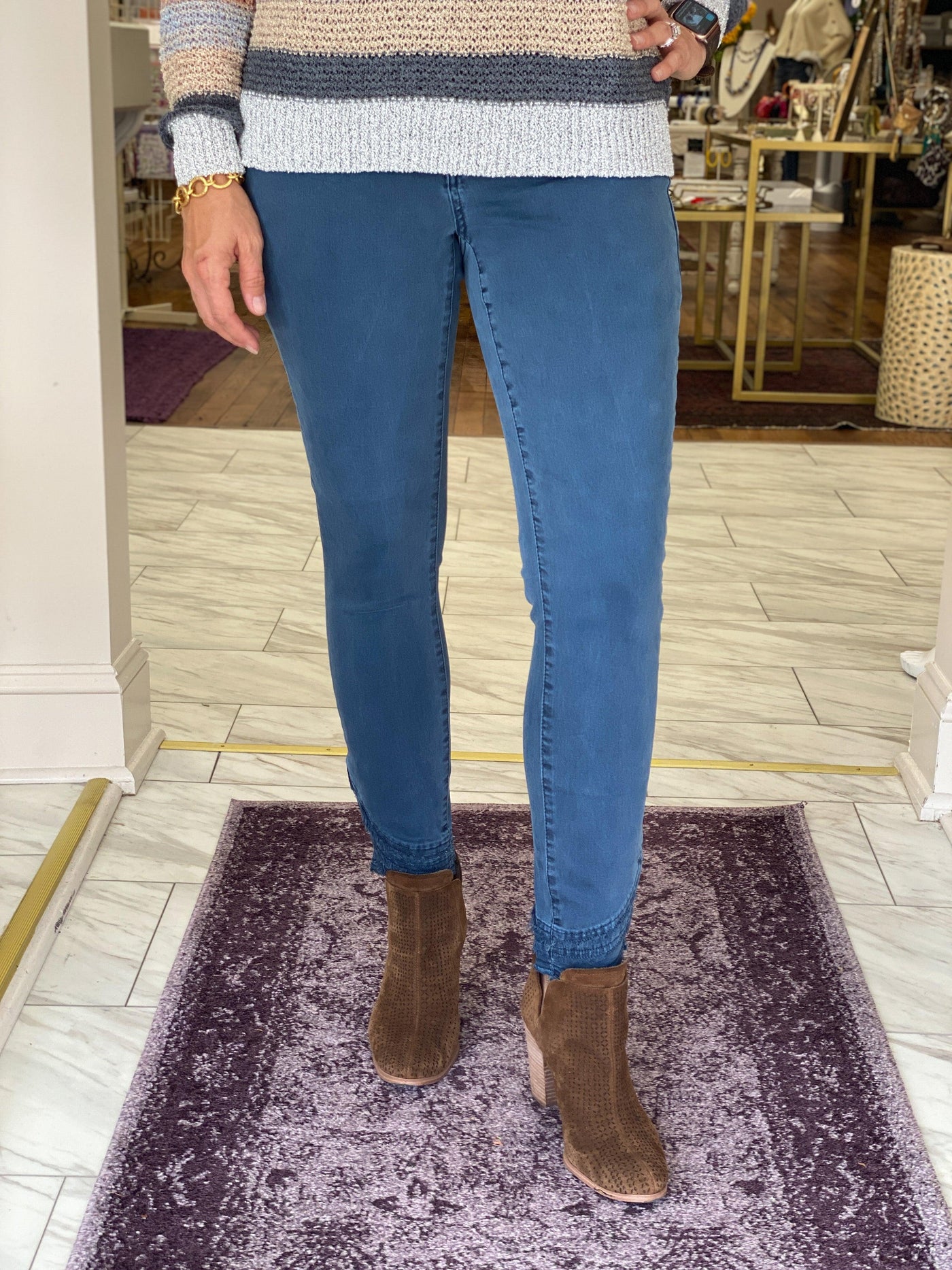 Model wearing balsam colored denim pants with frayed edge hem and brown booties.