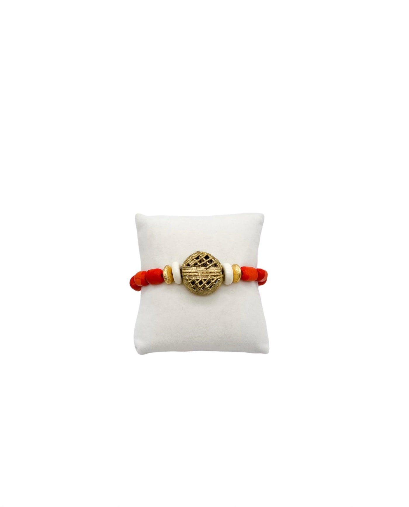 Stretch bracelet with orange short tube beads, flat gold beads, flat white beads and a large textured gold beads on a white display pillow