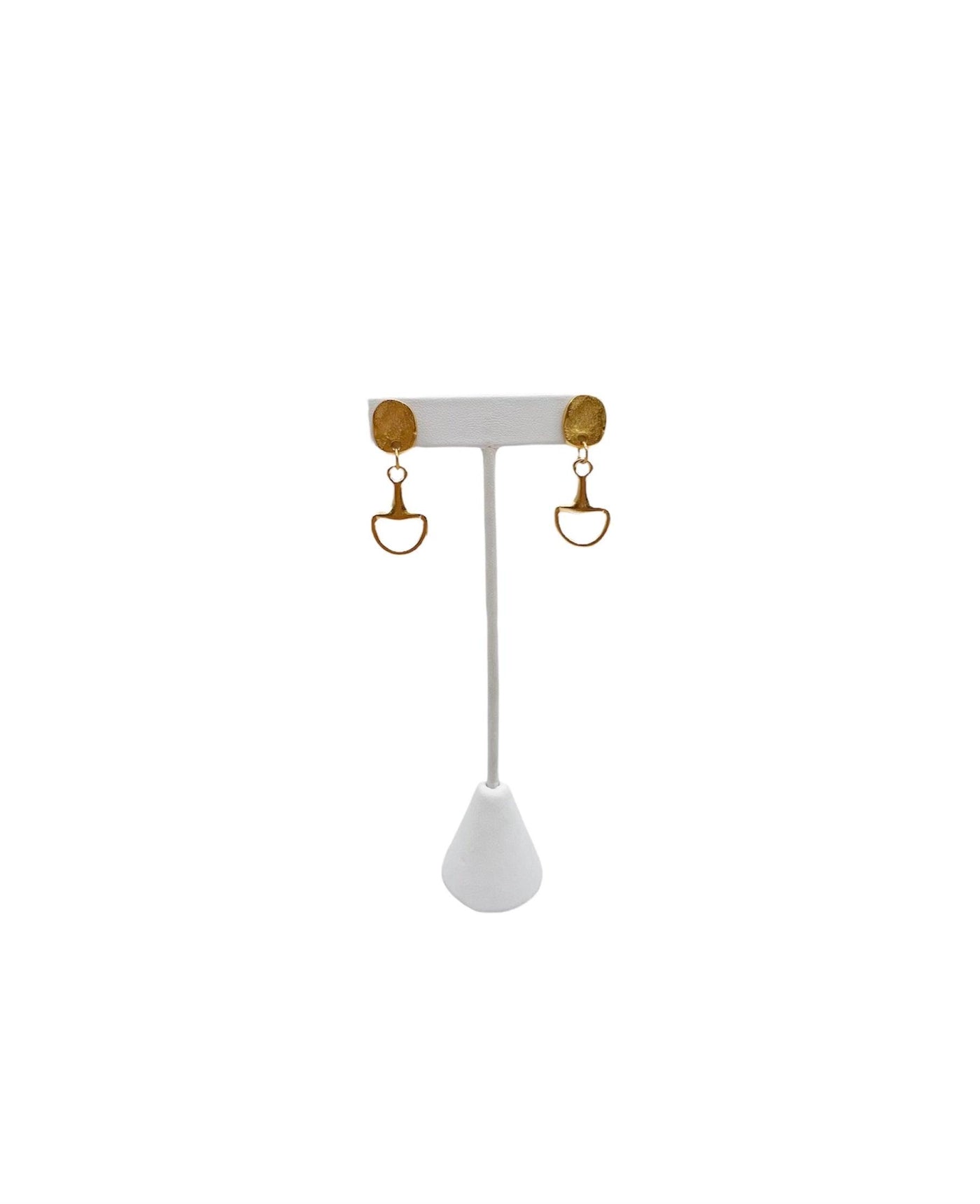 Gold stud and horse bit drop pendant earrings on a white earring stand