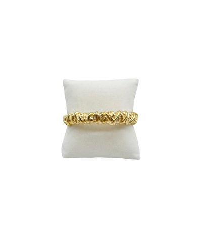 Textured gold bangle bracelet on a white display pillow