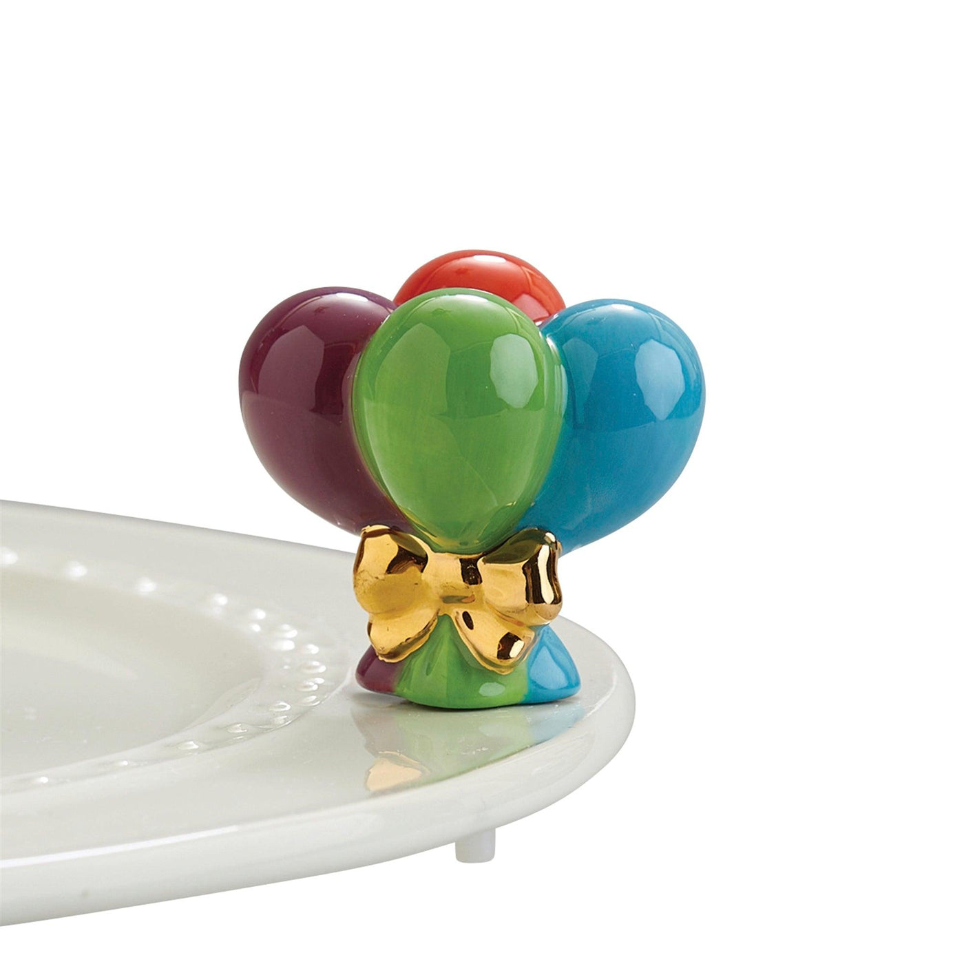 Red, purple, green, and blue ballon tied together with a gold bow mini for a Nora Fleming dish